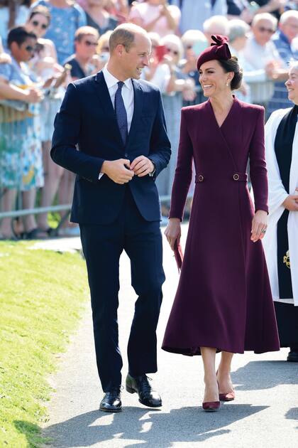 Los príncipes de Gales caminan por las calles de Pembrokeshire rumbo a la catedral de Saint David. Para la ocasión, Kate eligió un vestido-abrigo de la firma Eponine London, clutch de gamuza de Mulberry England, stilettos Gianvito Rossi y tocado de Sahar Millinery, todo en bordó, y el toque especial a su estilismo lo dio con los pendientes de perlas y diamantes que pertenecieron a Isabel II.