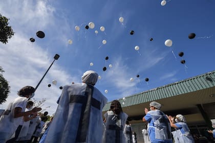 Los profesionales de la salud sostienen globos antes de liberarlos mientras honran a los colegas que murieron por el nuevo coronavirus, en las afueras del Hospital de la Universidad de Sao Paulo en Brasil, el 12 de mayo de 2020