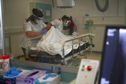 Los radiólogos Emma Parker y Gemma Ainsworth preparan a la paciente Doreen Mount para una radiografía en el departamento de rayos X del Royal Blackburn Teaching Hospital en Blackburn, noroeste de Inglaterra el 14 de mayo de 2020, como personal del servicio nacional de salud (NHS) en Gran Bretaña luc
