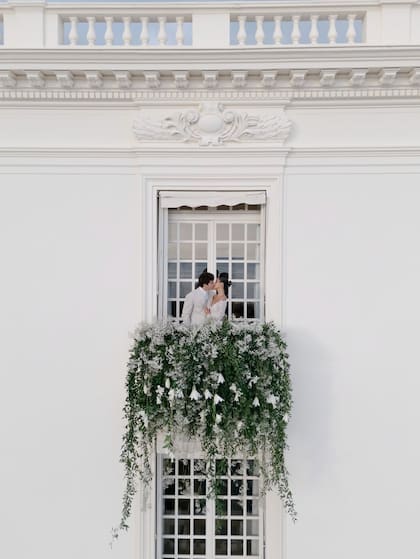 Los recién casados se funden en un beso de película en uno de los balcones decorado flores blancas