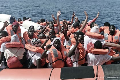 Los refugiados del "Aquarius" saludan luego de ser rescatados por la Marina italiana