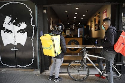 Los repartidores esperan los pedidos en la puerta de los locales para luego entregarlos