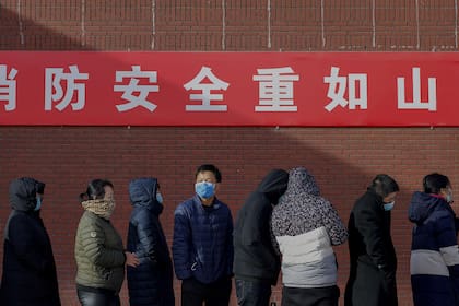 Residentes usando barbijo en una fila en China
