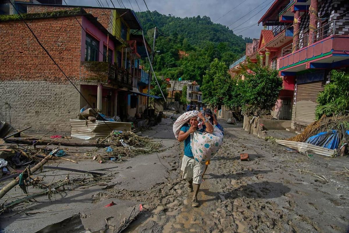 Los residentes transportan sus pertenencias mientras se dirigen a zonas más seguras tras las repentinas inundaciones en Devighat, en el distrito nepalí de Nuwakot