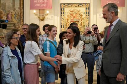 Los reyes de España, Letizia (centro derecha) y Felipe VI (derecha), saludan a turistas durante la inauguración de una exposición sobre el 10mo aniversario del inicio de su reinado, en el Palacio Real, en Madrid, el 20 de junio de 2024. (AP Foto/Bernat Armangue, Pool)