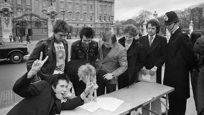 Los Sex Pistols mostraban irreverencia contra la monarquía y aquí firman un contrato con su representante, Malcolm McClaren, frente al Palacio de Buckingham