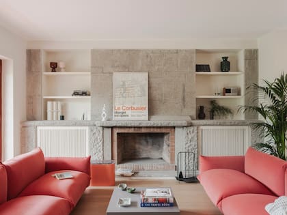 Los sillones ‘Marenco’ (Arflex) enmarcan el área social y aportan un guiño de color en un ambiente donde priman los neutros. Sobre la chimenea, lámina vintage de la Exposición de Arquitectura de Nápoles en el Palacio Real, 1978.