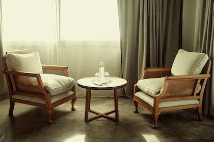 Los sofacitos franceses los compró en un mercado de pulgas y restauró para el hotel. La mesa ratona circular la hizo con una tapa de pinotea y espejo.