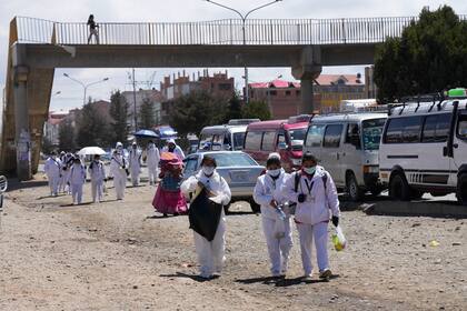 Los trabajadores de la salud caminan de regreso al centro de salud cercano para devolver su equipo de protección después de participar en una ceremonia de inicio de una campaña de vacunación contra el COVID-19 puerta a puerta en El Alto, Bolivia, el jueves 16 de septiembre de 2021.  (AP Foto/Juan Karita)