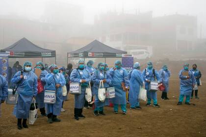 Los trabajadores de la salud sostienen hieleras con dosis de las vacunas Pfizer y Moderna para el COVID-19, así como vacunas contra la influenza, antes de ir de puerta en puerta para una campaña de vacunación en el barrio Ticlio Chico en las afueras de Lima, Perú, en el primer día oficial de invierno, el martes 21 de junio de 2022. (Foto AP/Martín Mejía)