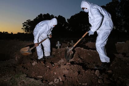 Los trabajadores del cementerio vestidos con ropa protectora entierran a una víctima de coronavirus en el cementerio de Sao Franciso Xavier en Río de Janeiro, Brasil, el 29 de mayo de 2020