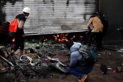 Los trabajadores del supermercado inspeccionan los daños causados por el fuego después de que estallaron los enfrentamientos entre la policía antidisturbios y los manifestantes antigubernamentales en Puno, Perú, el 9 de enero de 2023. (Juan Carlos CISNEROS / AFP)