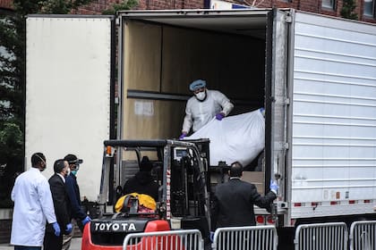 Los trabajadores médicos llevan un cuerpo a un camión refrigerado afuera del Hospital de Brooklyn el 31 de marzo de 2020 en la ciudad de Nueva York. Debido a un aumento en las muertes causadas por el Coronavirus, los hospitales están utilizando camiones refrigerados como morgues de turno.