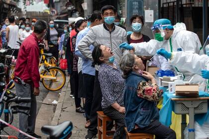 Los trabajadores médicos toman muestras de hisopos de los residentes para realizarles la prueba del coronavirus COVID-19 en una calle de Wuhan