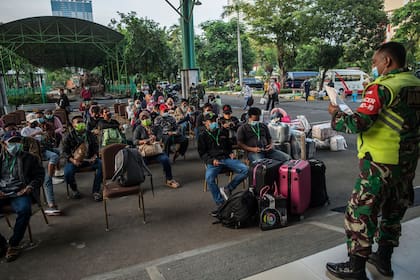 Los trabajadores migrantes que regresaron de Malasia y Singapur esperan la detección de Covid-19 en Surabaya el 28 de abril, antes de ser puestos en cuarentena