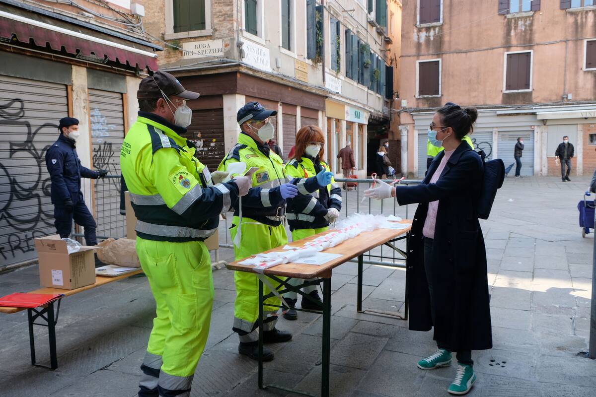 Los trabajadores municipales distribuyen máscaras y guantes en el mercado de Rialto, ya que la región del Véneto implementó nuevas restricciones para los mercados al aire libre para prevenir la propagación de la enfermedad por coronavirus (COVID-19), en Venecia, Italia, el 4 de abril de 2020.