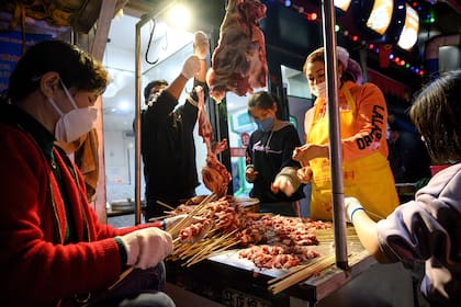 Los trabajadores que usan mascarillas hacen una barbacoa en un mercado en Wuhan, en la provincia central china de Hubei, el 4 de abril de 2020.