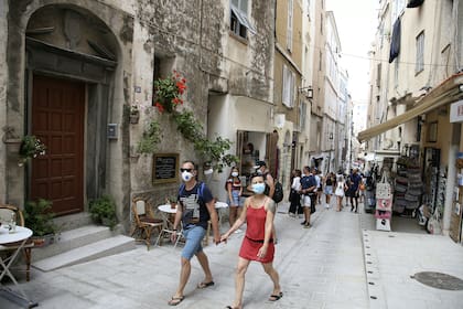Los turistas con tapabocas caminan por las calles de la antigua ciudad de Bonifacio el 5 de agosto de 2020, en la isla mediterránea francesa de Córcega, la primera y única ciudad de Córcega donde la máscara es obligatoria para evitar la propagación del coronavirus