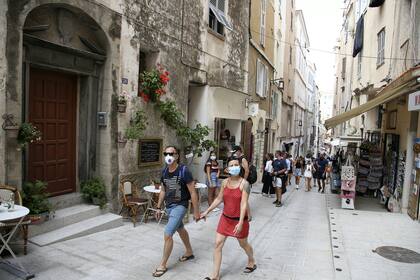 Los turistas con tapabocas caminan por las calles de la antigua ciudad de Bonifacio el 5 de agosto de 2020, en la isla mediterránea francesa de Córcega, la primera y única ciudad de Córcega donde la máscara es obligatoria para evitar la propagación del coronavirus
