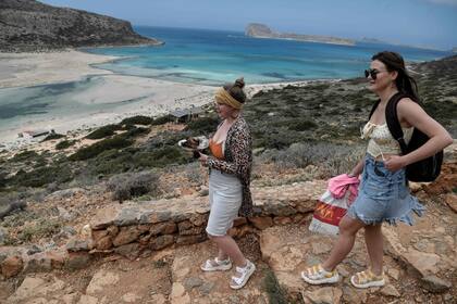 Los turistas llevan sus comidas mientras caminan hacia la playa de Balos y su laguna en la parte noreste de la isla de Creta