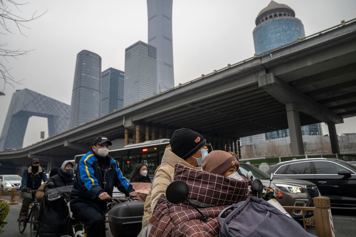 Los viajeros con máscaras faciales esperan en una intersección en el distrito central de negocios de Beijing