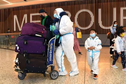 Los viajeros internacionales que usan equipo de protección personal (PPE) llegan al aeropuerto Tullamarine de Melbourne, el 29 de noviembre de 2021, cuando Australia registra sus primeros casos de la variante Ómicron del coronavirus