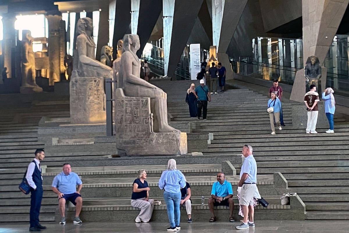Los visitantes caminan junto a estatuas colosales del antiguo Egipto a lo largo de la Gran Escalinata del Gran Museo Egipcio en Guiza, Egipto