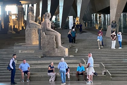 Los visitantes caminan junto a estatuas colosales del antiguo Egipto a lo largo de la Gran Escalinata del Gran Museo Egipcio en Guiza, Egipto