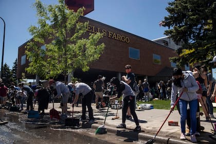 Los voluntarios ayudan a limpiar el agua de una sede del banco Wells Fargo el sábado 30 de mayo de 2020 en Minneapolis, que fue destruida la noche anterior durante las protestas contra el asesinato de George Floyd