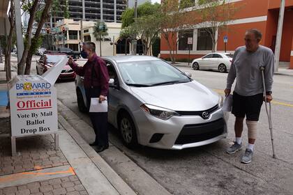 Los votantes depositan sus boletas en el buzón de votación por correo en el Condado de Broward, en Fort Lauderdale