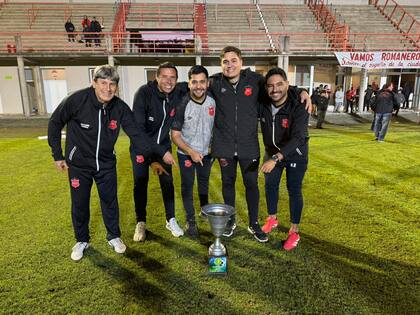 Lucas Batistuta con su cuerpo técnico y el trofeo de campeón