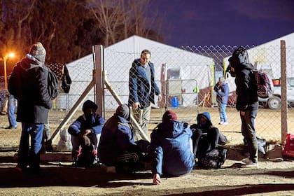 Lucas Castelli, ministro de Trabajo de Neuquén, conversa con personas que esperan para ingresar al lugar donde pasarán la noche