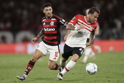 Lucas Piovi of Argentina's Estudiantes de La Plata, right, is challenged by De Arrascaeta of Brazil's Flamengo during a Copa Libertadores quarterfinal soccer match at Maracana stadium, in Rio de Janeiro, Thursday, Sept. 18, 2025. (AP Photo/Bruna Prado)