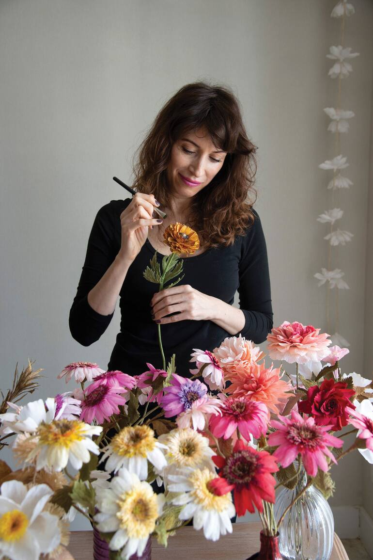 Luciana Lubreto, aplicando detalles de ajustes y coloreado en una flor de marimonia de papel.