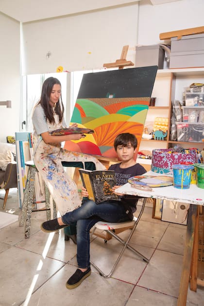 Luciana tiene su taller en su casa. En la foto, pintando mientras el mayor de sus hijos, Jerónimo, lee uno de sus libros favoritos, El arte de la guerra.