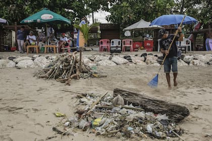 Lugareños limpian la playa durante la temporada de vacaciones en la playa de Kuta en Bali, Indonesia