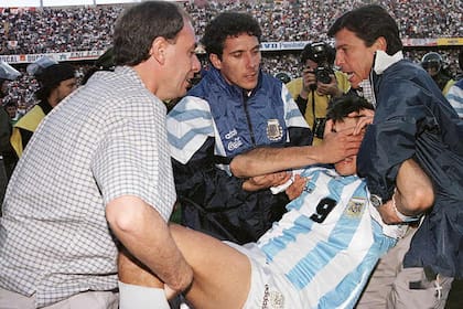 Luis Seveso, Diego Cagna y Daniel Passarella ayudan a Julio Cruz tras ser agredido en el final del partido entre Argentina y Bolivia, en 1997