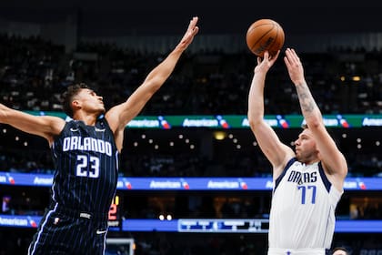 Luka Doncic (77), de los Mavericks de Dallas, dispara sobre el intento de tapa de Tristan da Silva (23), del Magic de Orlando, durante la primera mitad del juego de baloncesto de la NBA, el domingo 3 de noviembre de 2024, en Dallas. (AP Foto/Gareth Patterson)