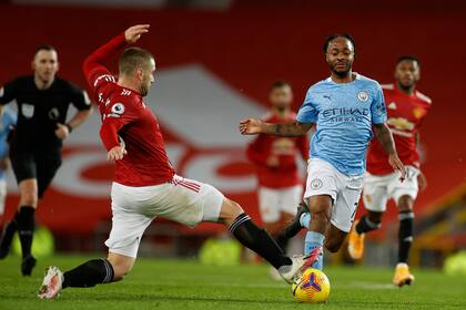 Raheem Sterling intenta llevarse la pelota ante la marca de Luke Shaw, en una escena del clásico de Manchester entre United y City, por la Premier League.