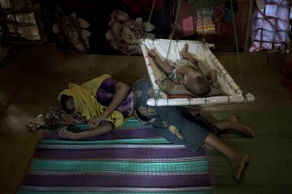 M, acostada en el piso, descansa mientras su bebé se despierta de su siesta. Fue violada por seis soldados en Myanmar después de que estrangularon a su hijo de dos años. Luego descubrió que estaba embarazada y tuvo un varón. Cuando le contó a su marido lo que le había pasado, él la culpó y le dijo q