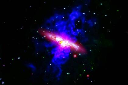 En azul y rosa se ve la salida de un flujo de gas de unos 20.000 años luz de largo
