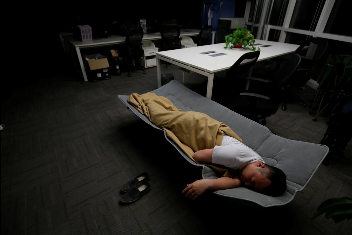 Ma Zhen Guo, un ingeniero de sistemas en Renren crédito Management Co., duerme en una cama plegable en la oficina después de terminar el trabajo temprano en la mañana