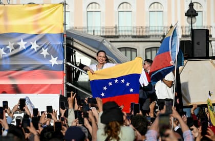 Machado sostiene una bandera venezolana mientras sus seguidores se congregan en la Puerta del Sol de Madrid