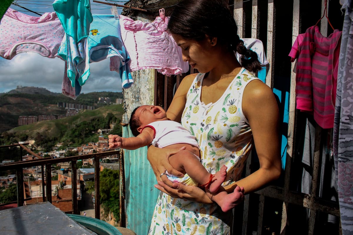 Madre soltera Yarimar Buitrago (19), toma sol con su bebé de un mes en su casa del barrio El Nazareno de la populosa comunidad de Petare en Caracas el 28 de junio de 2020