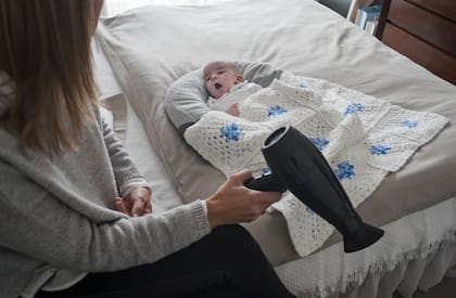 Una madre calma a su hijo con el ruido de un secador de pelo