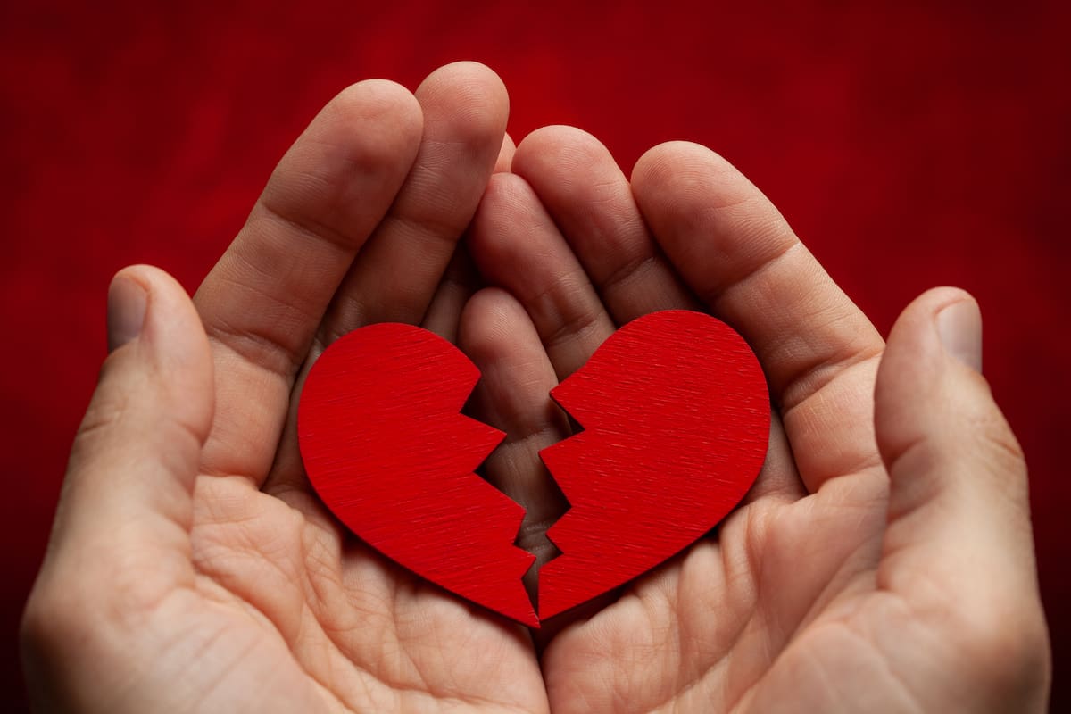 Man holds a broken heart in his hands. Crack in the red heart, Breaking the relationship.