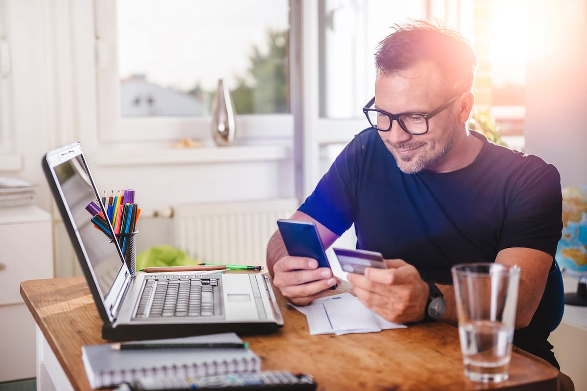 Man paying with credit card on smart phone at home office
