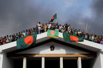 Manifestantes antigubernamentales exhiben la bandera nacional de Bangladesh al irrumpir en el palacio de la primera ministra Sheikh Hasina en Dhaka el 5 de agosto de 2024