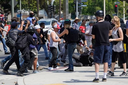 Manifestantes antivacuna, a la izquierda, se enfrentan a contramanifestantes durante una protesta contra la obligatoriedad de las inoculaciones anti-COVID-19, frente al ayuntamiento en Los Ángeles, el sábado 14 de agosto de 2021. (AP Foto/Damian Dovarganes)