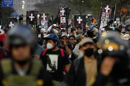 Manifestantes cargan féretros de cartón en representación de las víctimas de la violencia política durante una protesta (Archivo)
